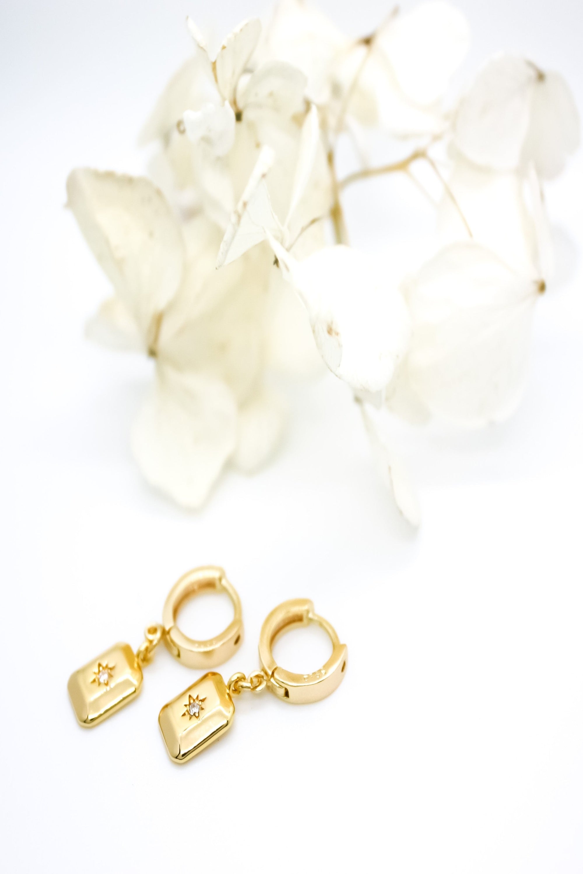 "Gold-filled huggie earrings with classic bohemian design, featuring a rectangle charm with star burst in centre.""
