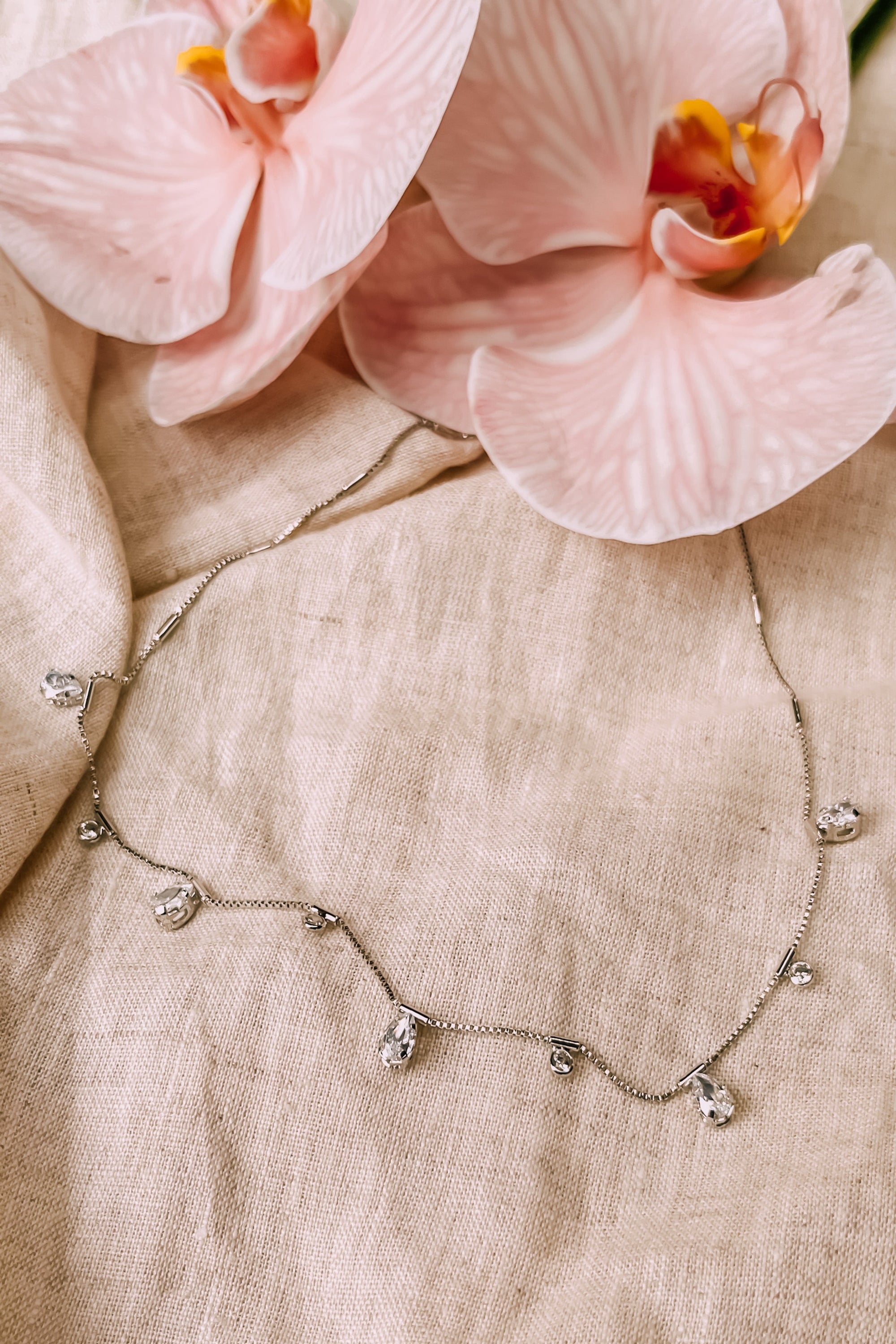  "White gold-filled necklace with tear-drop charms and delicate chain design."